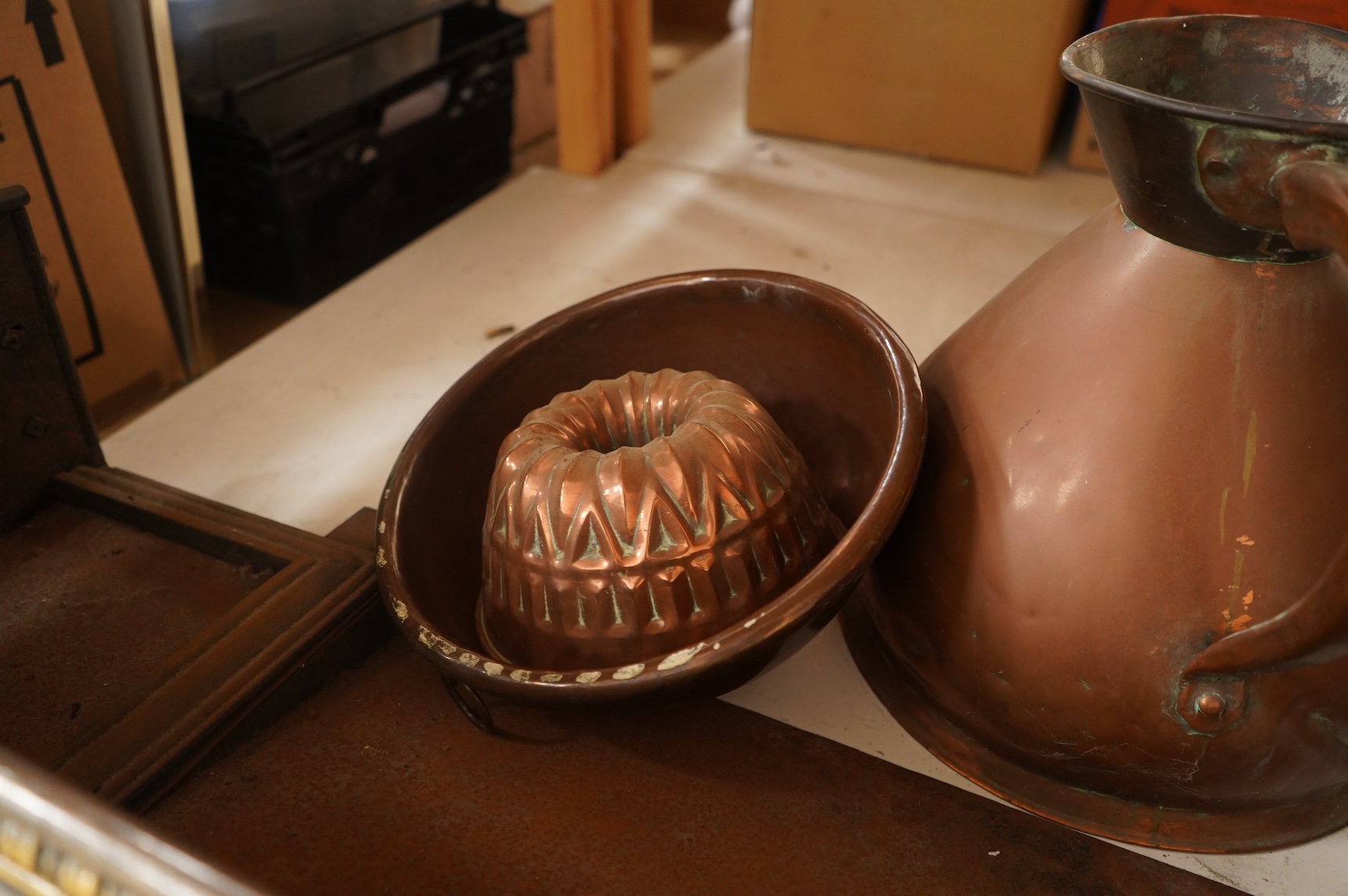 A collection of metalware to include a steel and brass fender, a helmet scuttle, 19th century jelly mould and a harvest jug